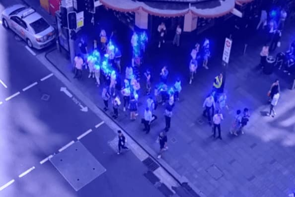 A heatmap of pedestrians gathered on a sidewalk, with clusters of people more brightly coloured than the rest of the scene. 